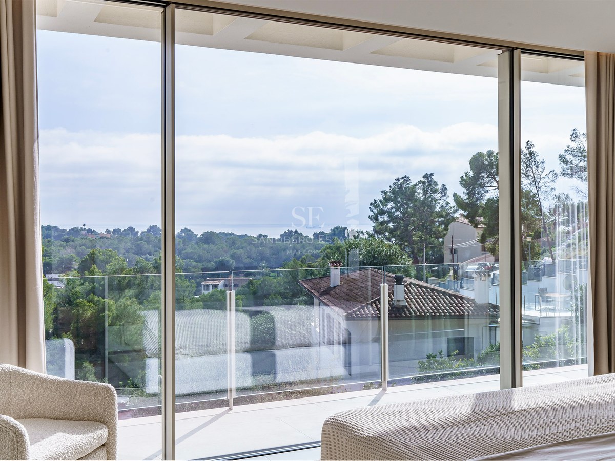 Chambre de luxe avec baies vitrées offrant une vue sur le paysage méditerranéen et la mer.