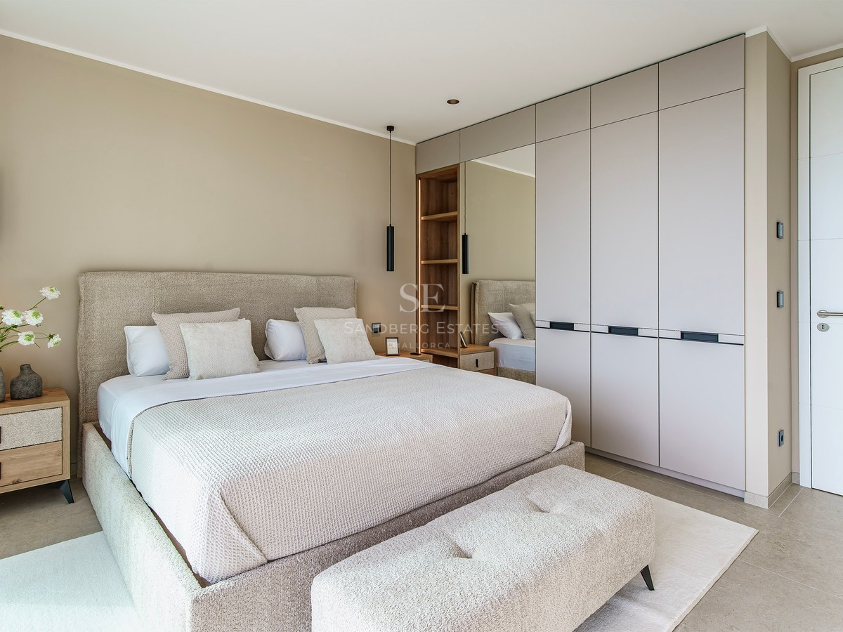Chambre moderne avec un grand lit rembourré beige, des placards intégrés et des suspensions noires élégantes.