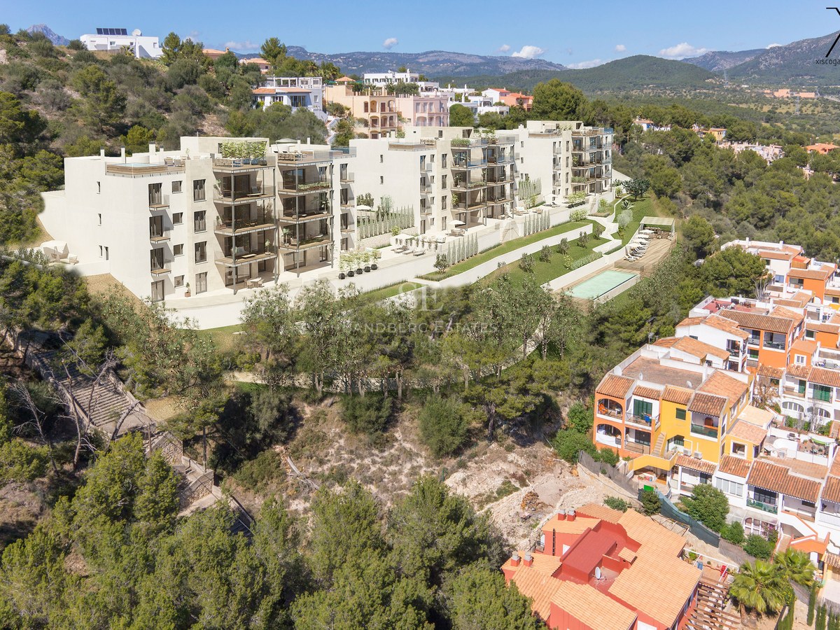 Vue aérienne d'un complexe d'appartements moderne sur une colline avec terrasses privées et piscine commune.