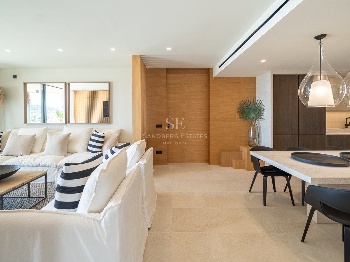 Salon élégant avec canapés en lin blanc, boiseries en chêne et coin repas avec suspensions design.