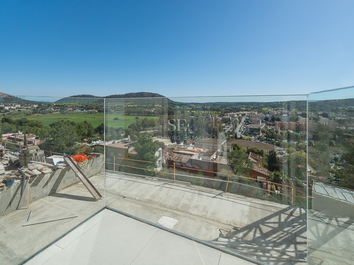 Terrasse en cours de finition avec garde-corps en verre surplombant une vallée et un village méditerranéen.