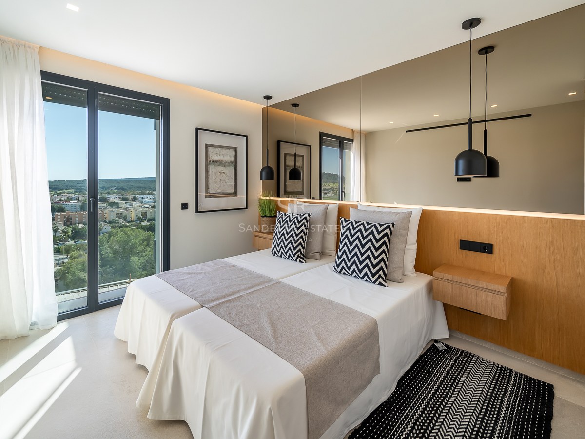 Chambre moderne avec lits jumeaux, tête de lit en bois, grand miroir et baie vitrée ouvrant sur une vue panoramique.