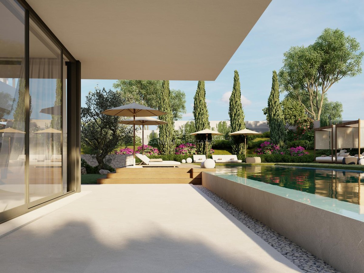 Luxury infinity pool with glass edge, wooden deck, and sun loungers overlooking a landscaped Mediterranean garden.
