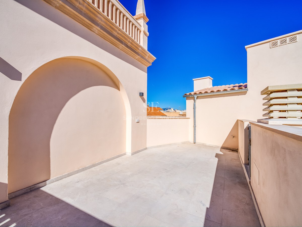 Terrasse de toit ensoleillée avec revêtement en pierre crème et arche sous un ciel bleu pur.