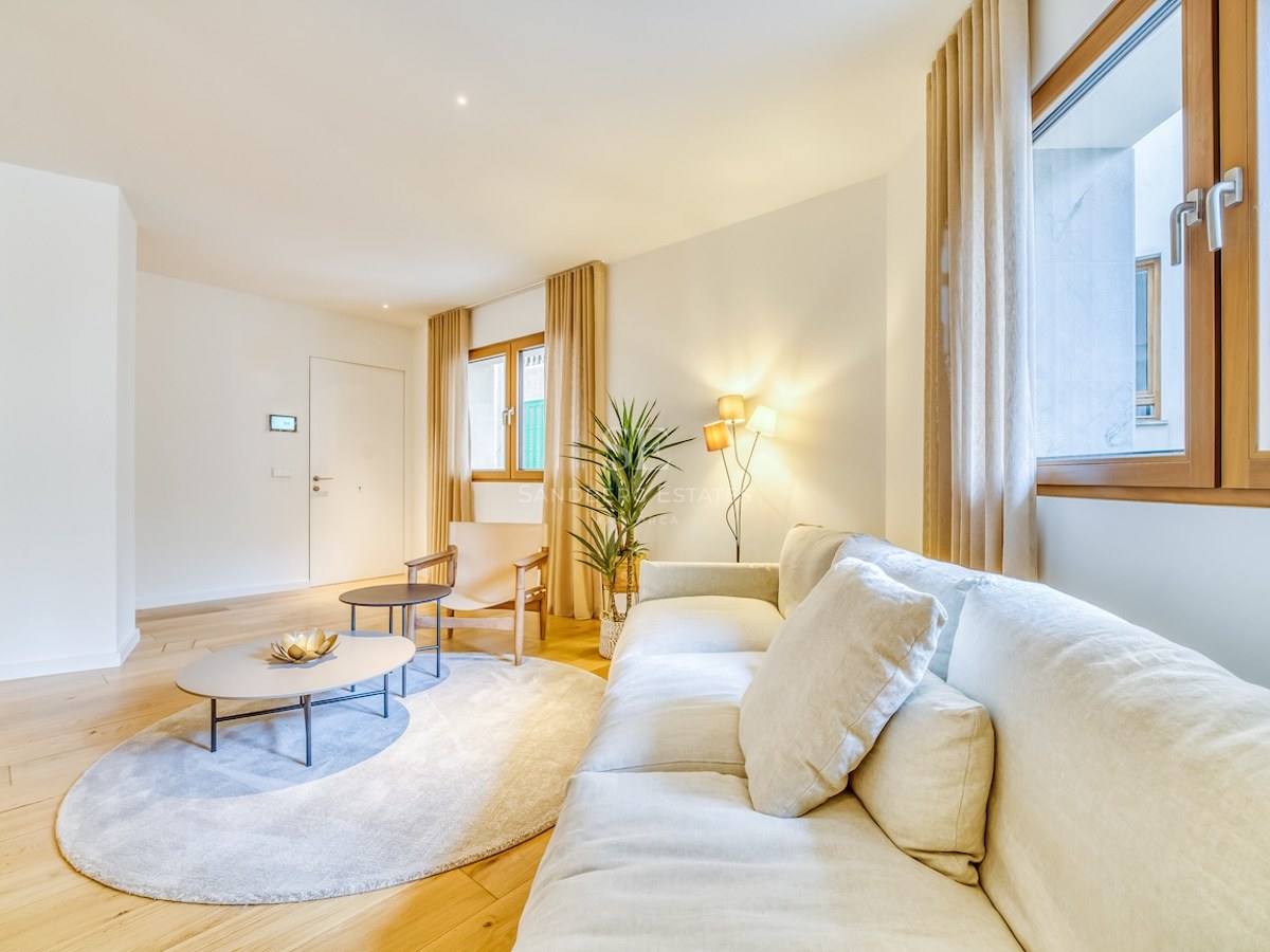 Salon lumineux avec canapé en lin blanc, parquet en chêne, cadres de fenêtres en bois et éclairage chaleureux.
