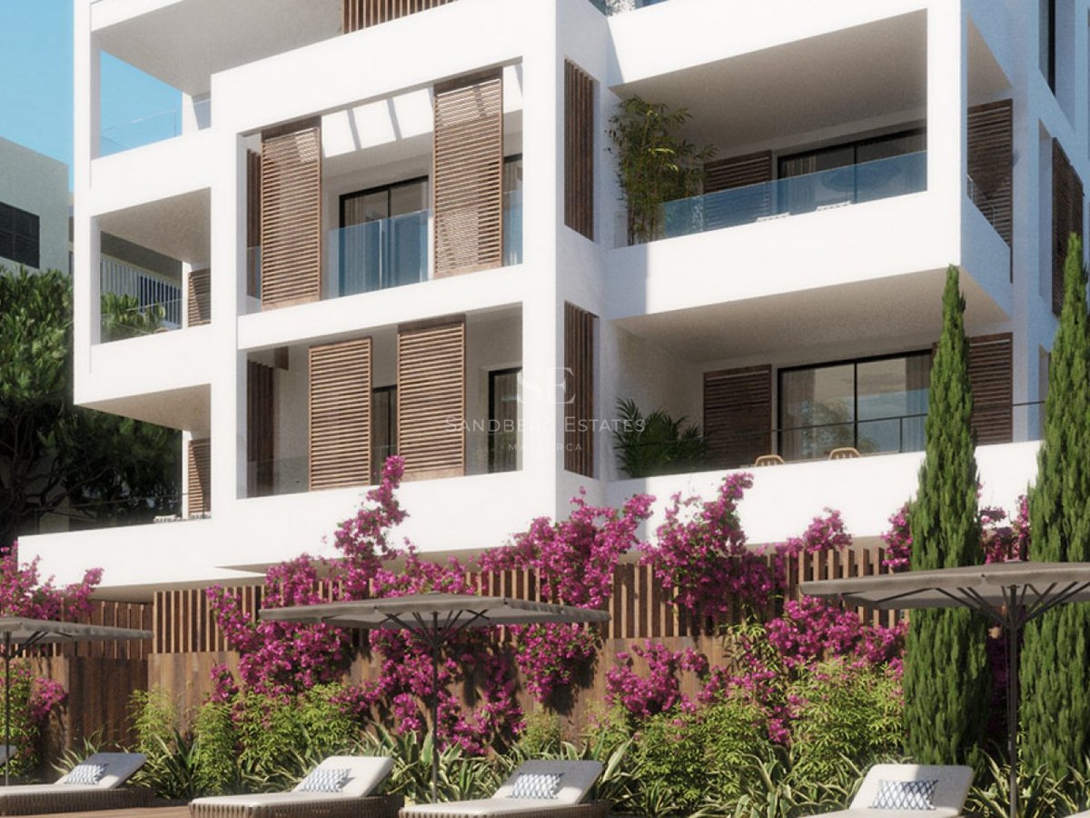 Modern white apartment building with wooden shutters, glass balconies, and a pool deck with sun loungers and pink flowers.