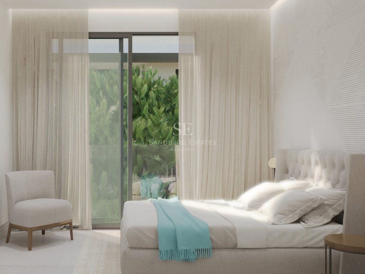 Modern bedroom with a tufted headboard, turquoise throw, armchair, and large windows looking onto lush green plants.