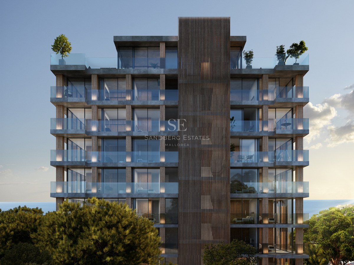 Modern multi-story building with glass balconies and wood accents surrounded by trees and sea views.