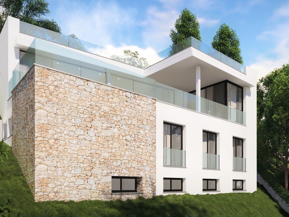 Villa blanca moderna en una colina verde con pared de piedra natural y barandillas de cristal.
