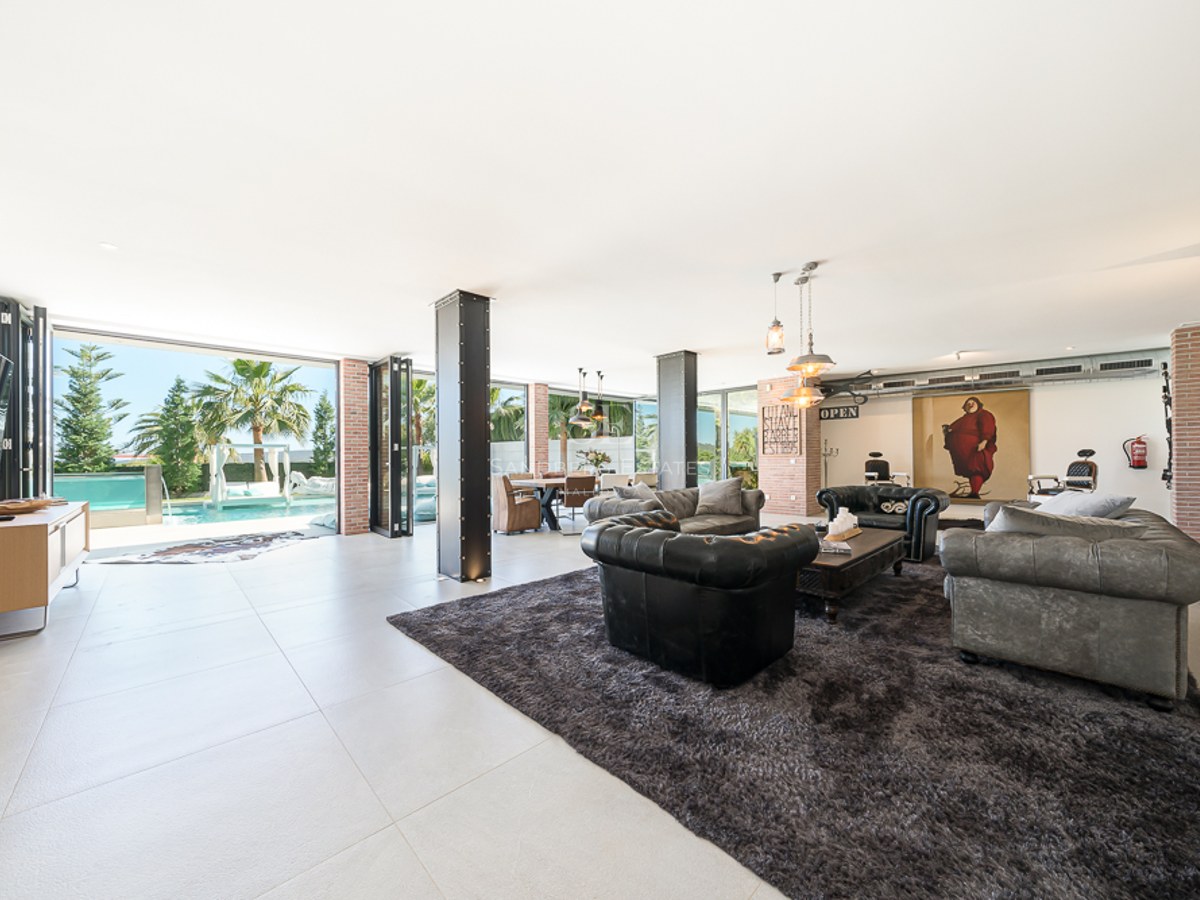 Vue aérienne d'une villa moderne avec piscine bleu vif, jardin luxuriant et architecture minimaliste. Vastes terrasses et abondance de lumière naturelle.