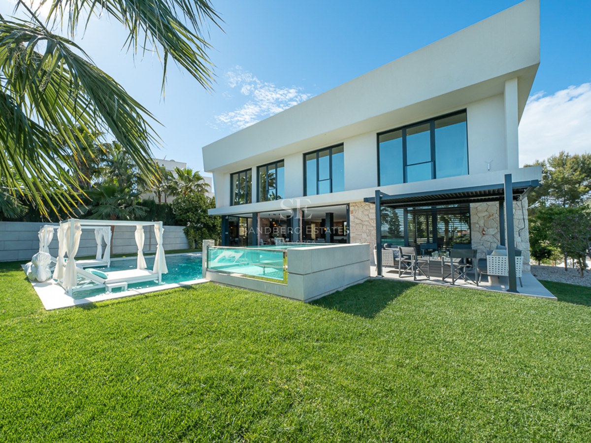Vaste salon avec baies vitrées, vue sur mer, parquet clair, cheminée et mobilier moderne dans des tons neutres.