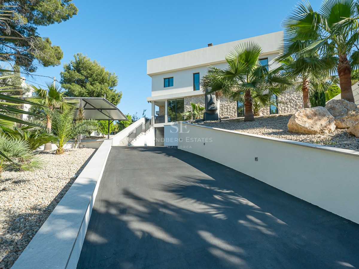 Grande piscine avec transats, jardin verdoyant et façade moderne d'une maison individuelle avec de grandes fenêtres. Ciel bleu dégagé.