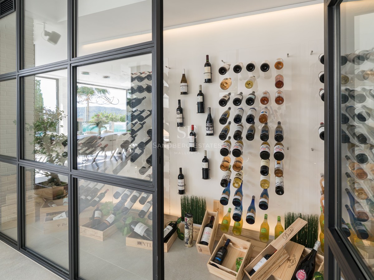 Cave à vin moderne vitrée avec cadres noirs, bouteilles sur supports minimalistes et caisses en bois.