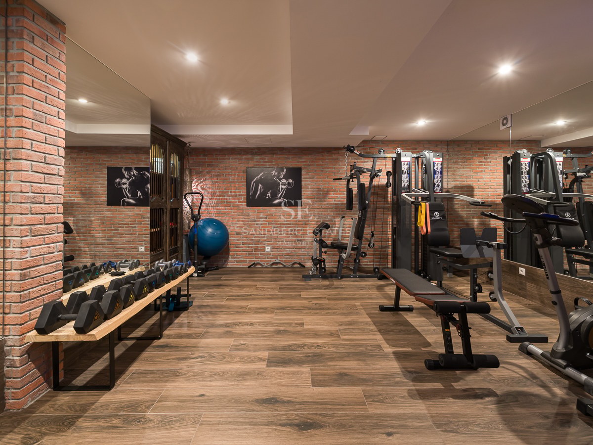 Salle de sport avec murs en briques, parquet, grands miroirs et équipements de fitness professionnels.