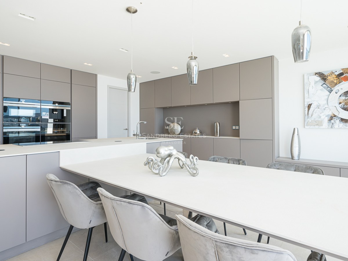 Cocina contemporánea con armarios color topo, una gran isla blanca y sillas de comedor de terciopelo gris.