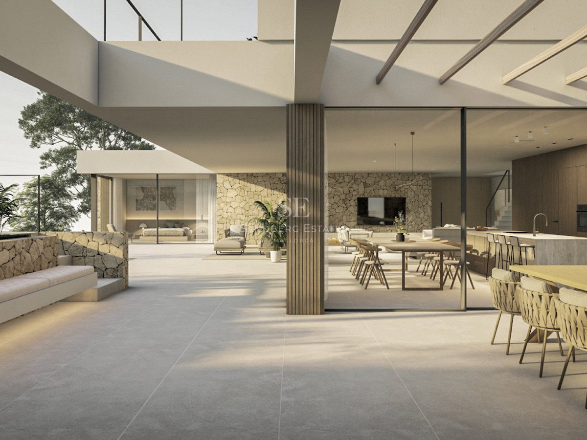 Terrasse de villa moderne avec murs en pierre et baies vitrées s'ouvrant sur un grand salon et une salle à manger.