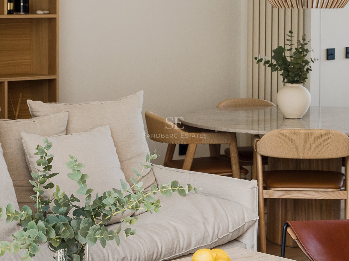 Sala de estar moderna con sofá beige, mesa de comedor de piedra y decoración minimalista con eucalipto.