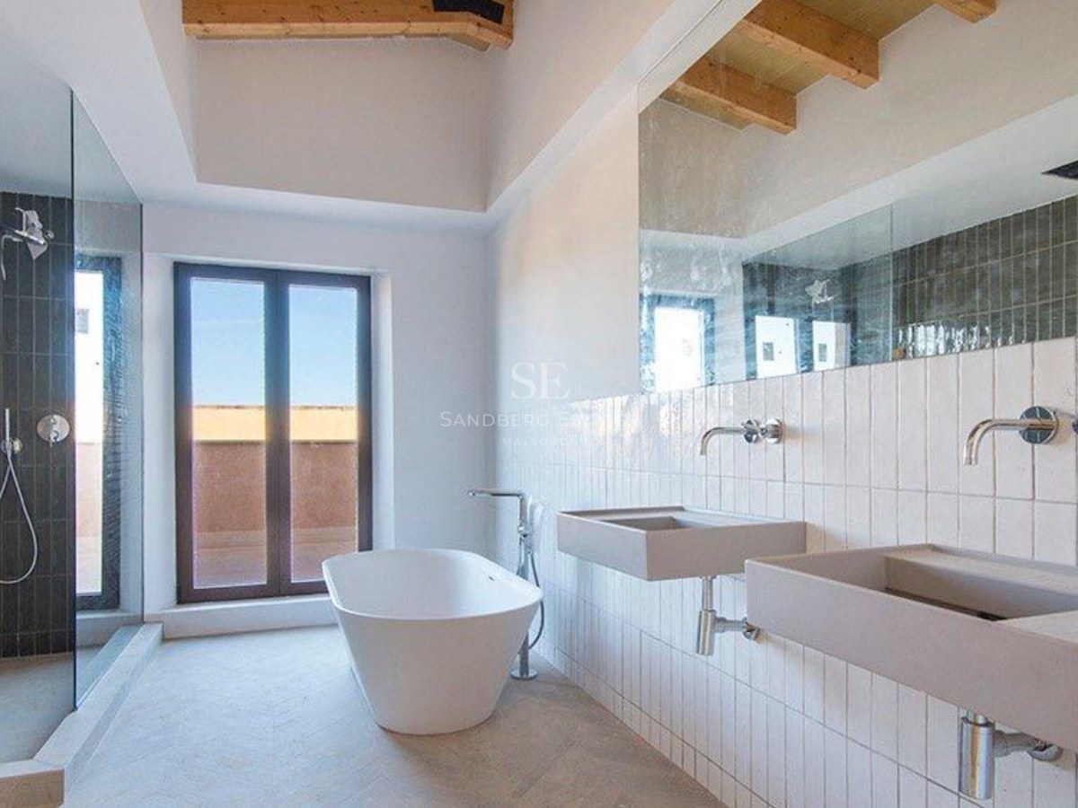 Minimalist bathroom featuring dual stone sinks, a white freestanding bathtub, and walk-in shower under wooden beams.