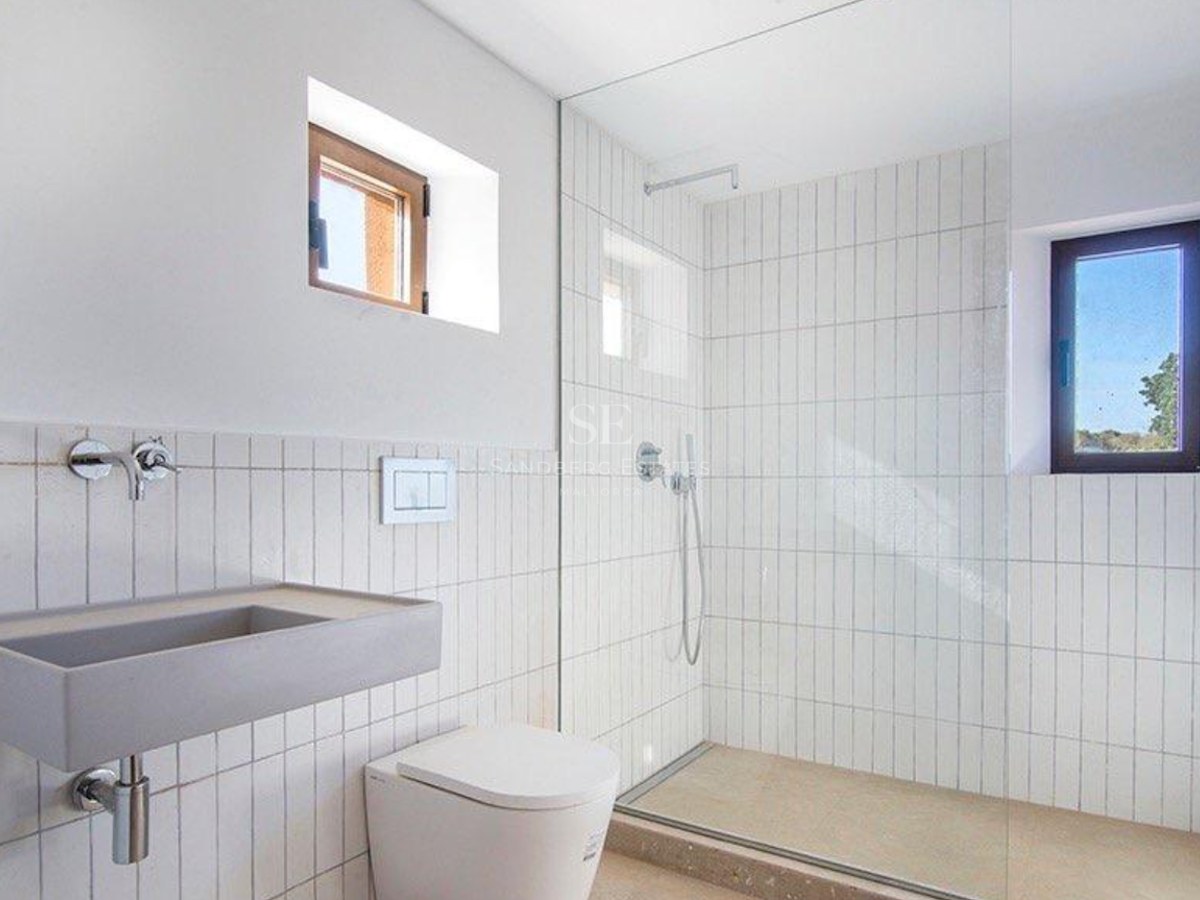 Contemporary bathroom featuring a walk-in shower with glass screen, vertical white tiles, and a gray stone sink.