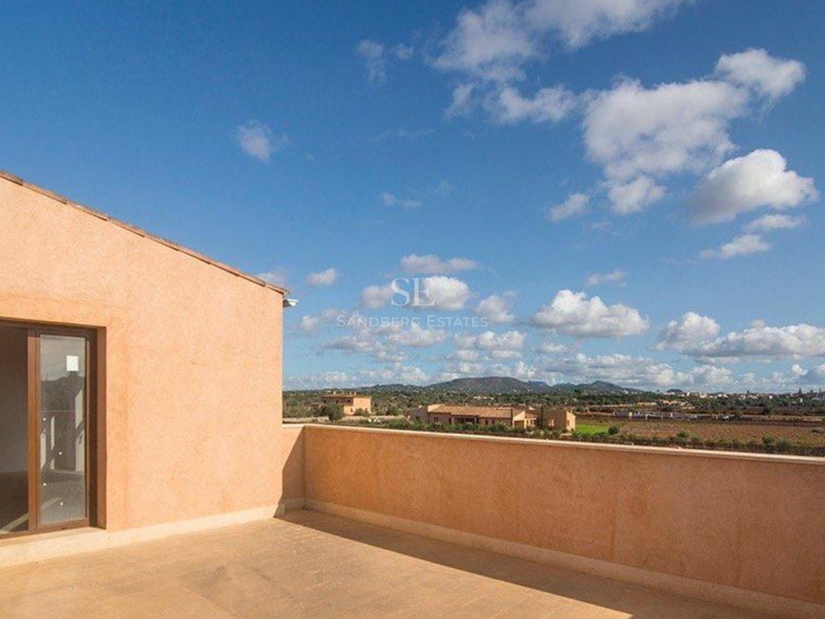 Spacious rooftop terrace featuring natural stone tiling, ochre walls, and sweeping views of the Mediterranean landscape.