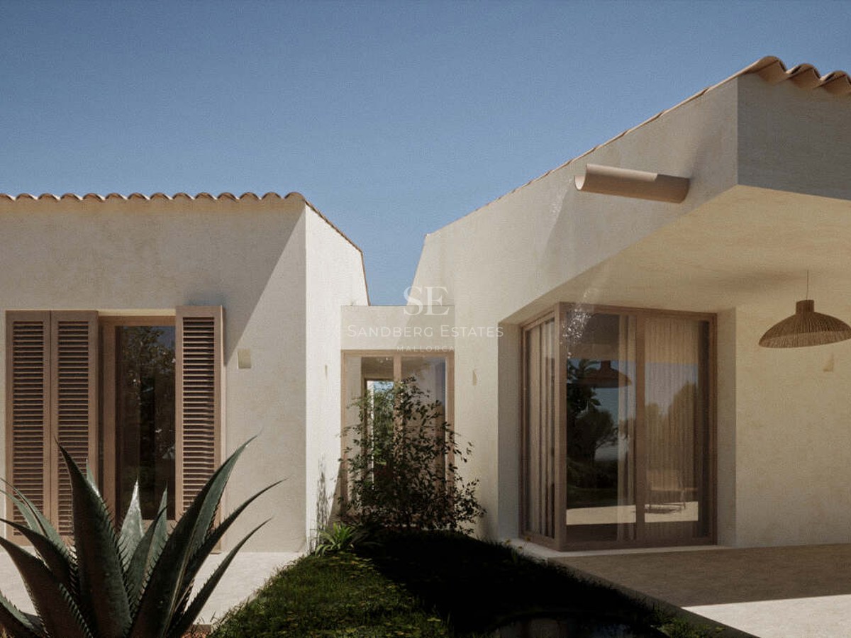 White villa exterior with terracotta roof tiles, wooden shutters, and large windows under a clear blue sky.