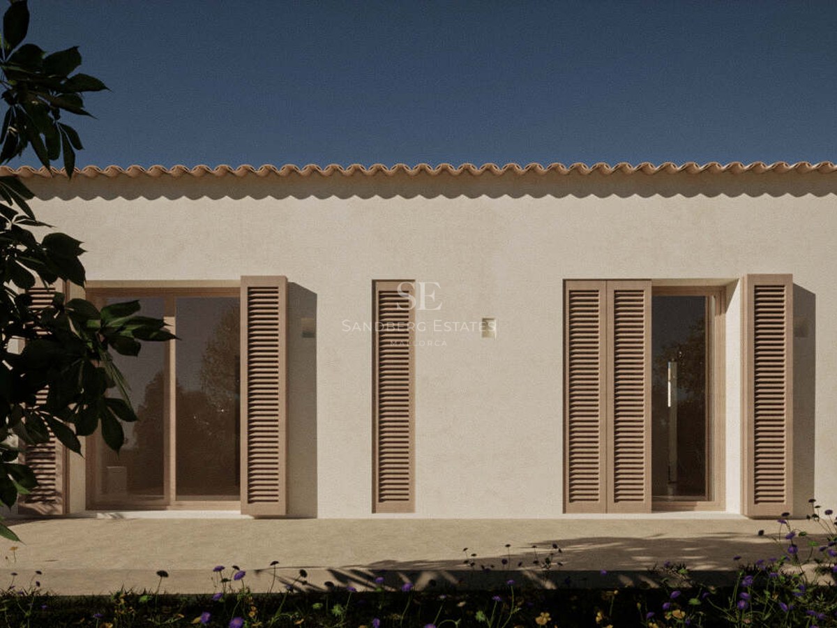 Cream-colored villa exterior featuring wooden Mallorquina shutters and terracotta roof tiles under a clear blue sky.