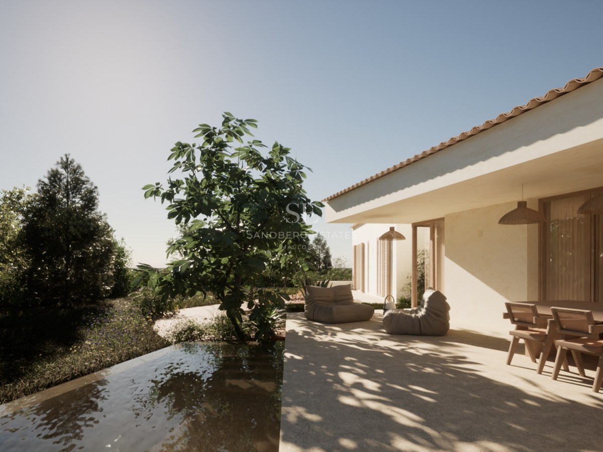 A sun-drenched stone terrace featuring a wooden dining set, lounge chairs, and a water feature edge under a clear sky.