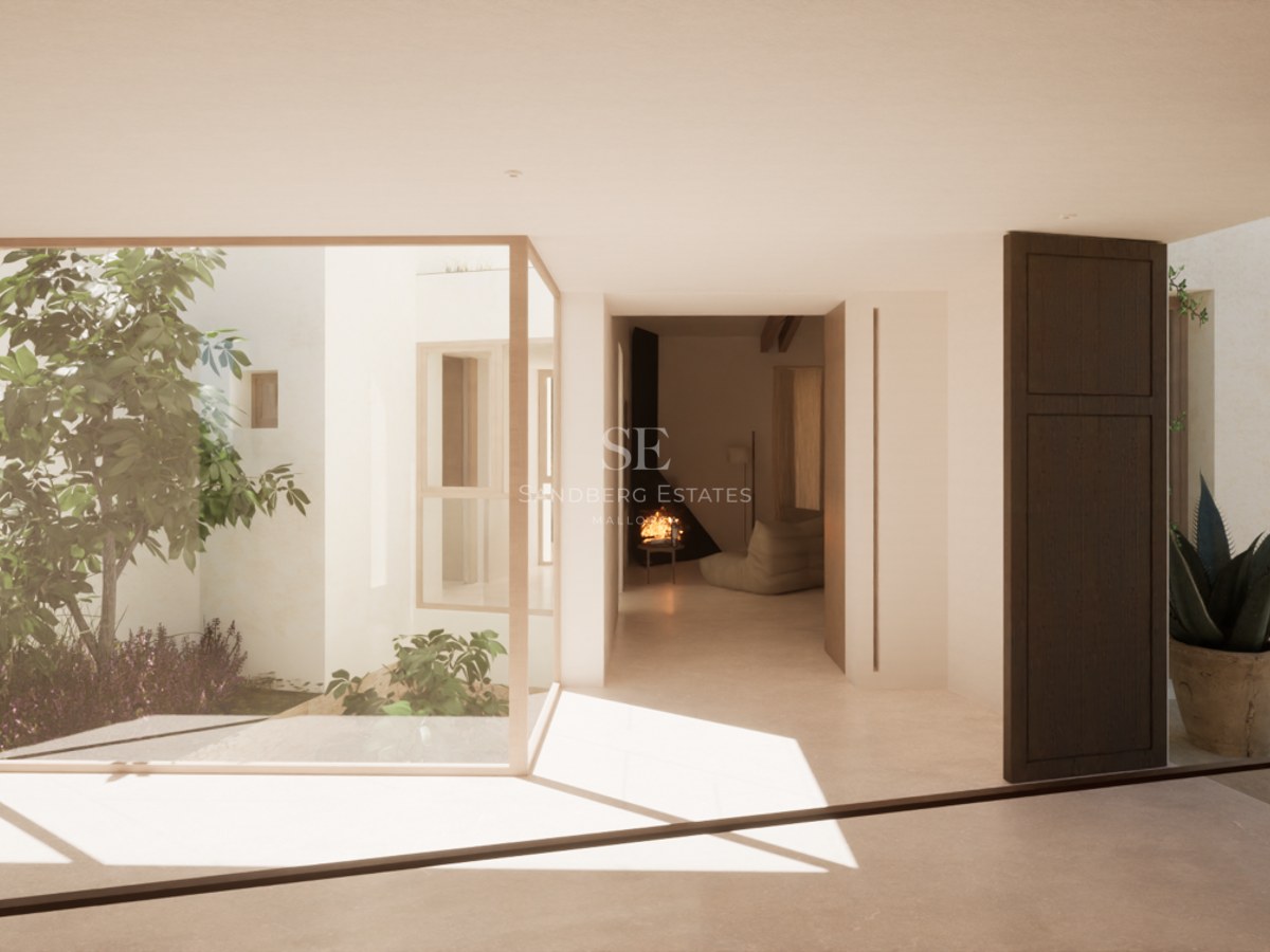Modern interior with large glass windows looking onto a sunlit internal garden with a minimalist fireplace in the background.