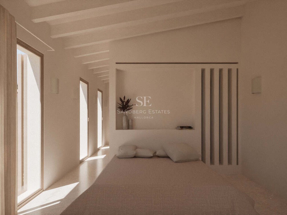 Sunlit minimalist bedroom with exposed white ceiling beams, floor-to-ceiling windows, and neutral linen bedding.
