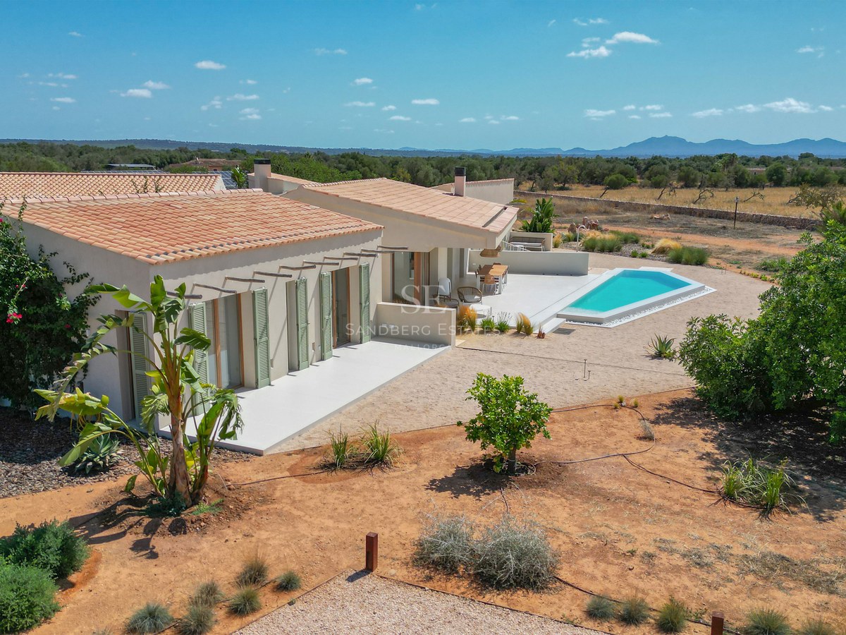 Aerial view of a modern single-story villa with terracotta roof, sage green shutters, and a geometric swimming pool.