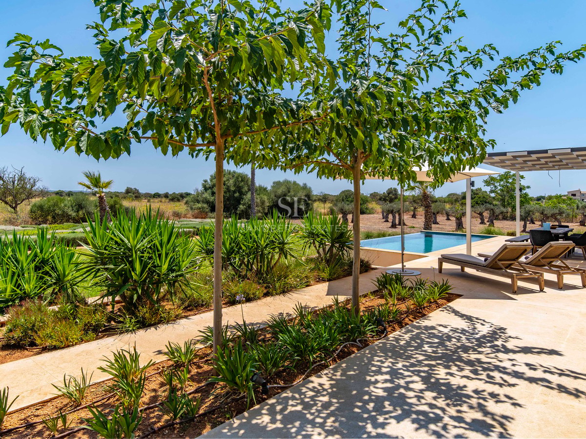 Terrasse en pierre naturelle avec transats au bord d'une piscine, entourée de jardins et de campagne.