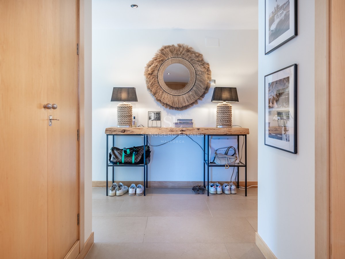 Hallway featuring a live-edge wood console table, sunburst mirror, and rope lamps on a light stone floor.