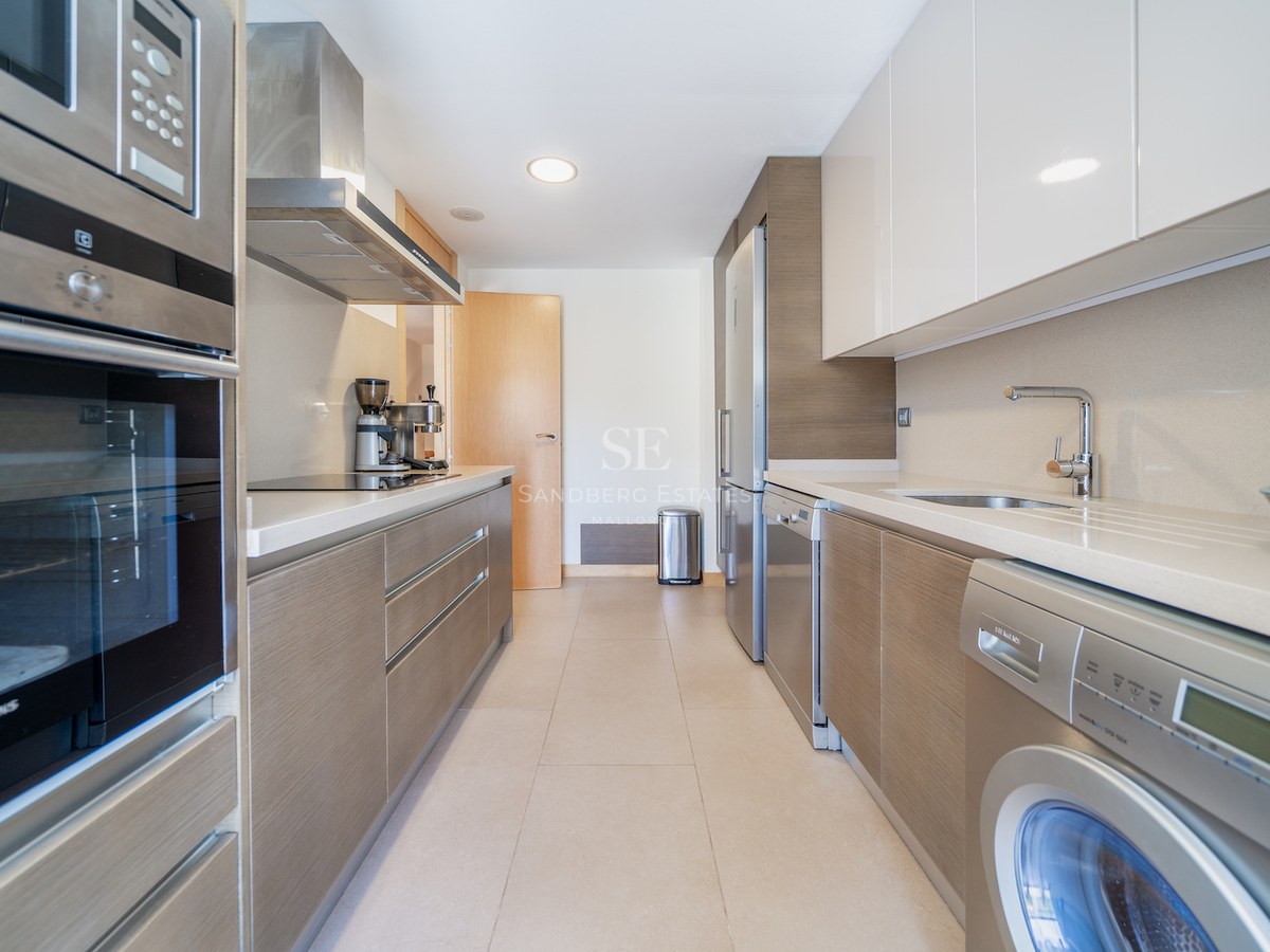 Galley-style kitchen featuring Siemens appliances, wood-grain lower cabinets, and white high-gloss upper cabinets.
