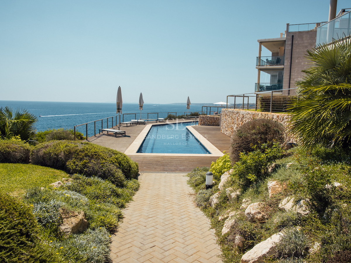 Long rectangular swimming pool on a wooden deck overlooking the Mediterranean sea with landscaped gardens.