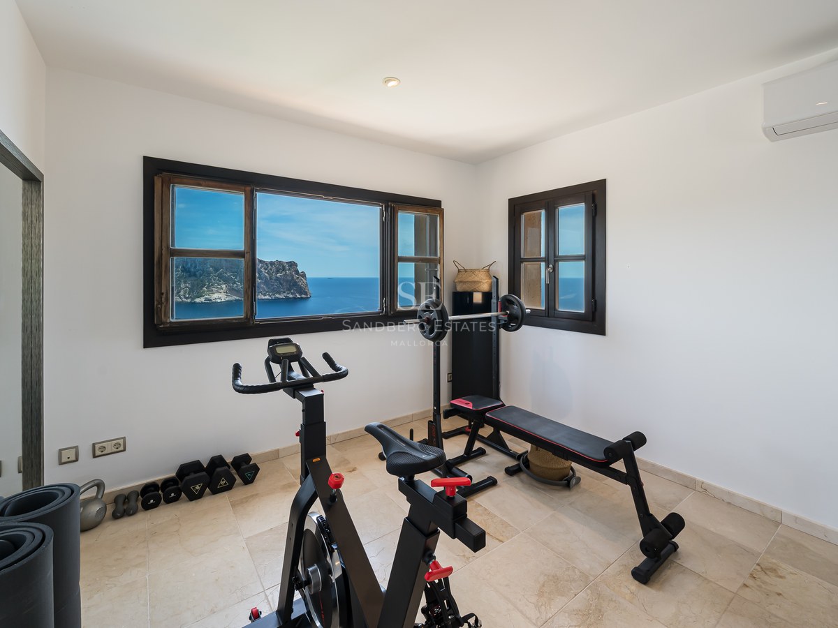 Salle de sport à domicile avec vélo d'appartement et banc de musculation devant une fenêtre donnant sur la mer.