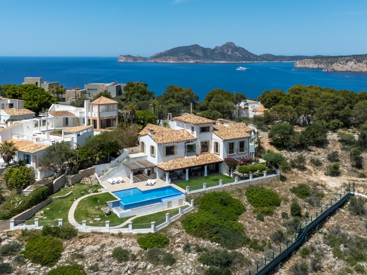 Vue aérienne d'une villa méditerranéenne blanche avec piscine surplombant la mer et les montagnes au loin.