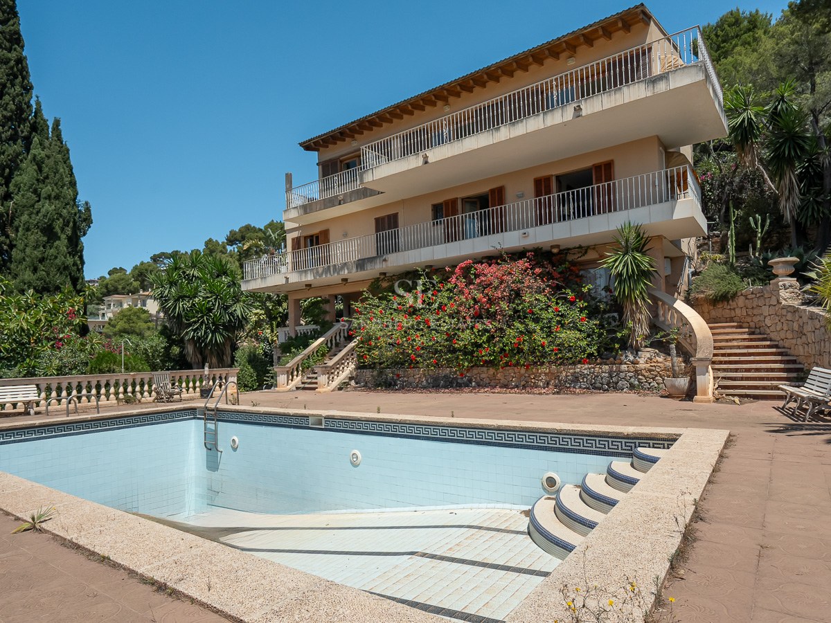 Gran piscina privada frente a una villa mediterránea de tres niveles con terrazas y jardines consolidados.