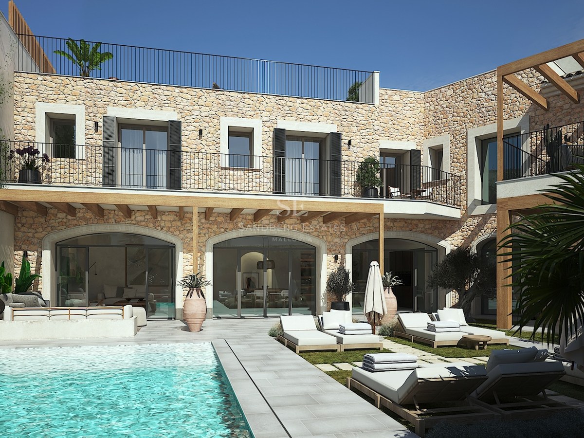 Piscine de luxe et terrasse avec façade en pierre naturelle et pergola en bois sous un ciel bleu.