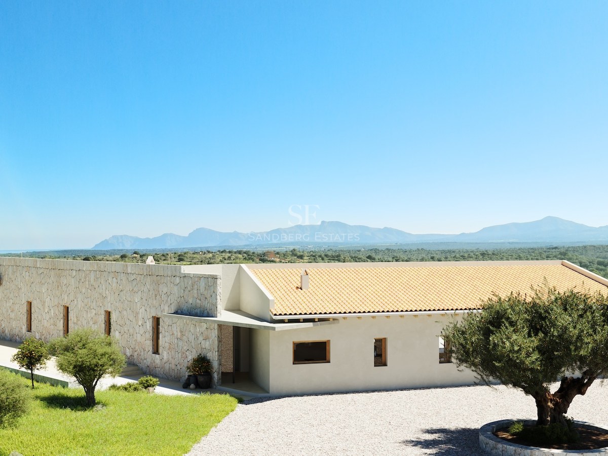 Moderne einstöckige Villa mit Natursteinmauern, Terrakotta-Dach und Olivenbäumen vor Bergkulisse.