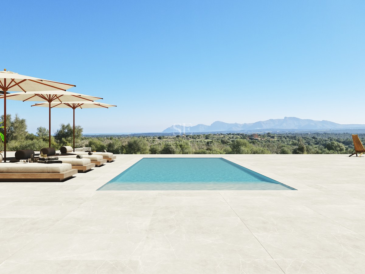 Rechteckiger Pool auf einer weiten Steinterrasse mit Blick auf eine Gebirgslandschaft unter klarem blauem Himmel.