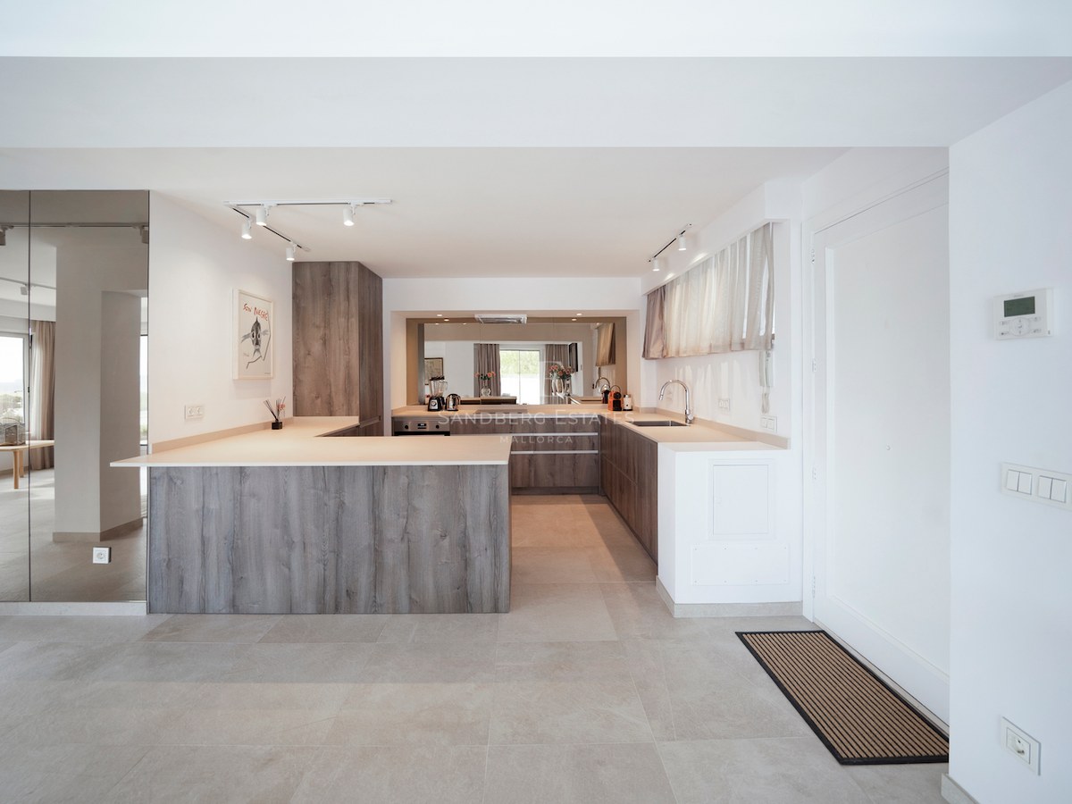 Cocina moderna con armarios de efecto madera gris, encimeras de piedra beige y suelos de gres porcelánico.