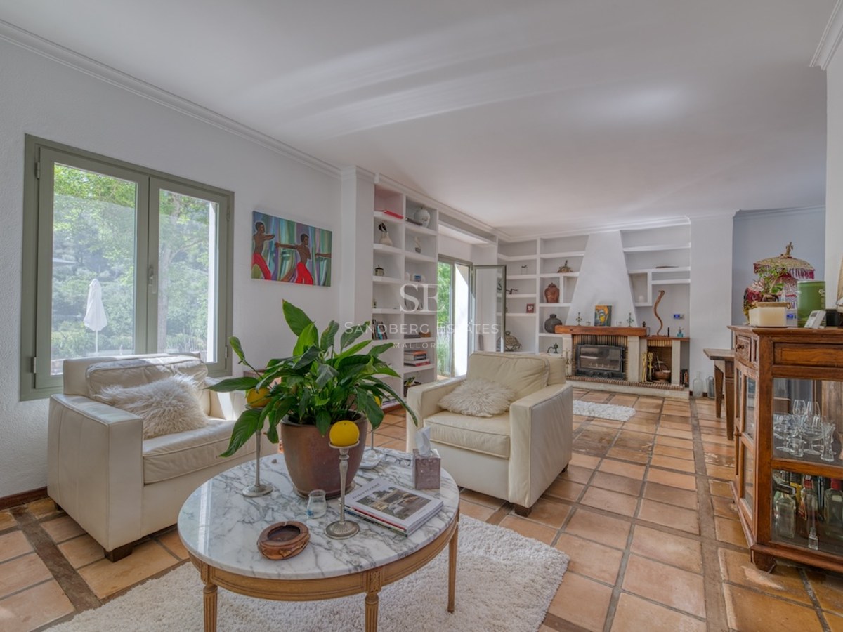 Salon spacieux avec fauteuils en cuir, table en marbre et cheminée sur un sol traditionnel en terre cuite.
