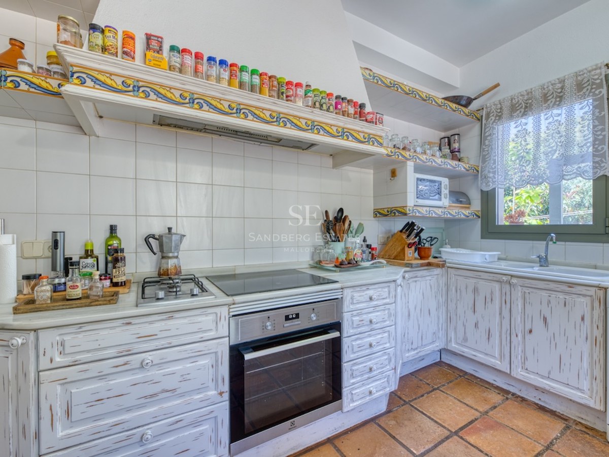 Cuisine de style méditerranéen avec meubles en bois blanchi, sol en terre cuite et bordures en céramique.