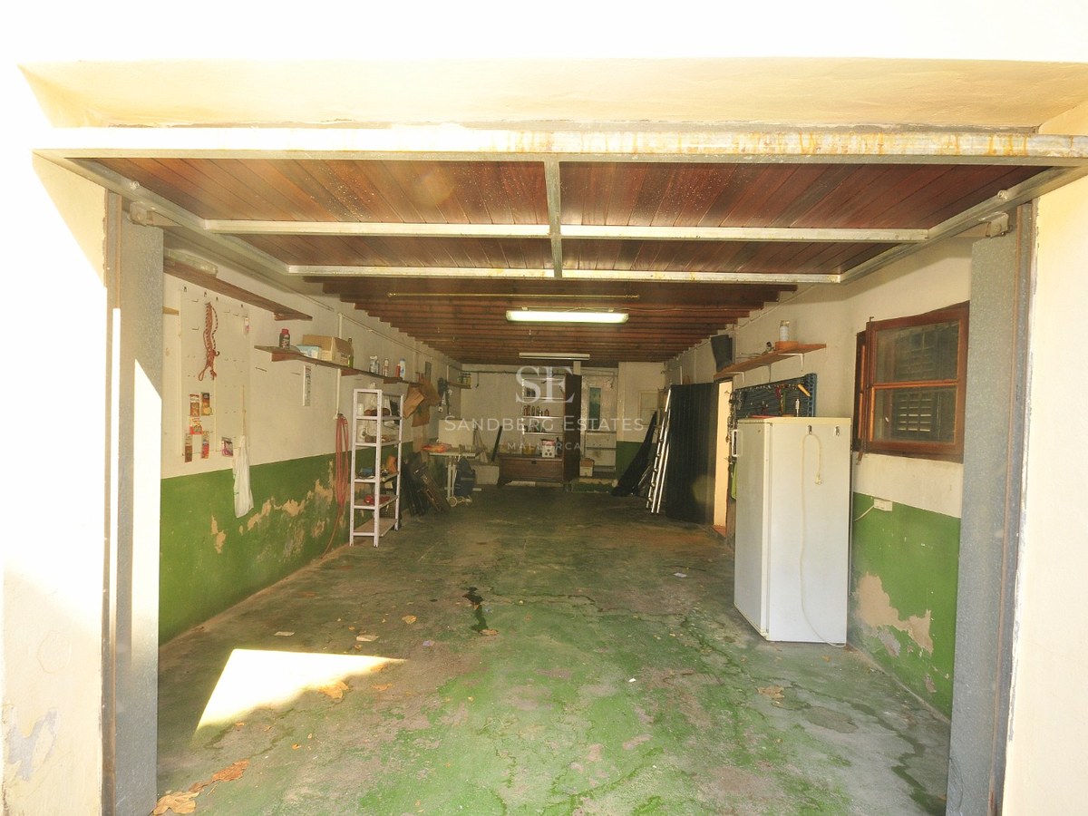 Interiör av ett rymligt garage med grönt betonggolv, trätak och förvaringshyllor.
