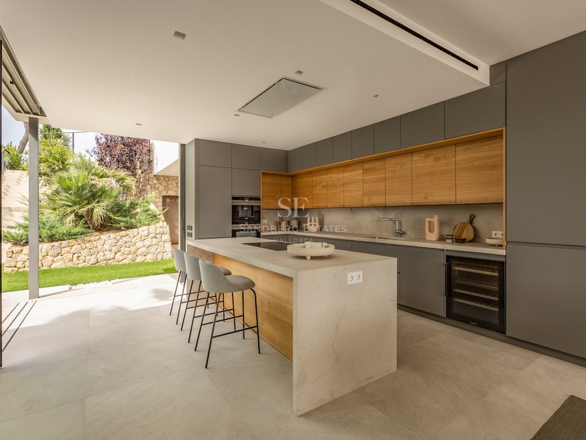 Modern grey and wood kitchen featuring a large central island with seating and direct access to the garden.