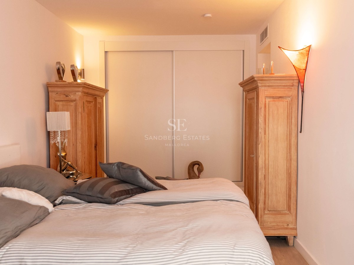 Chambre lumineuse avec grand lit, deux armoires en bois et placards intégrés sous un éclairage d'ambiance chaleureux.