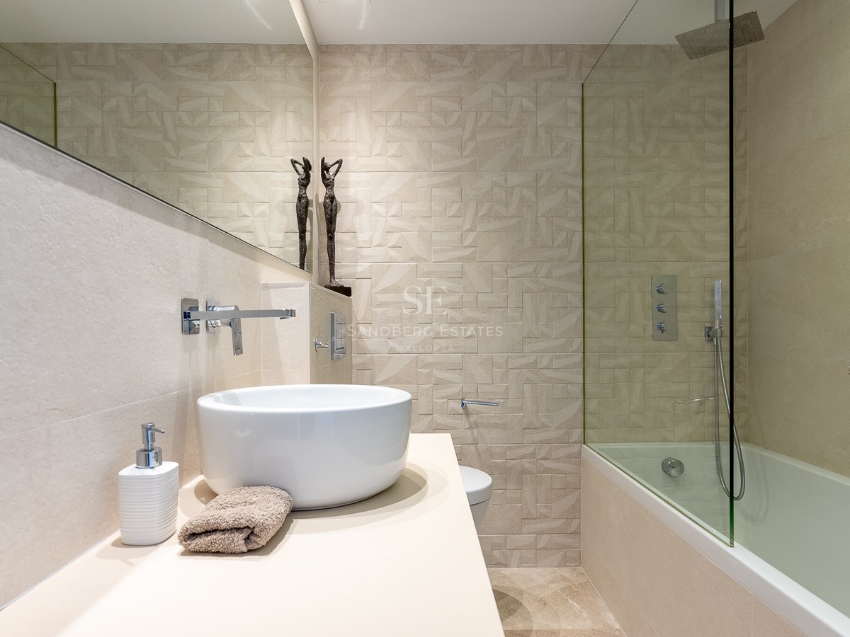 Salle de bains moderne avec vasque à poser, grand miroir et mur en carrelage géométrique texturé.