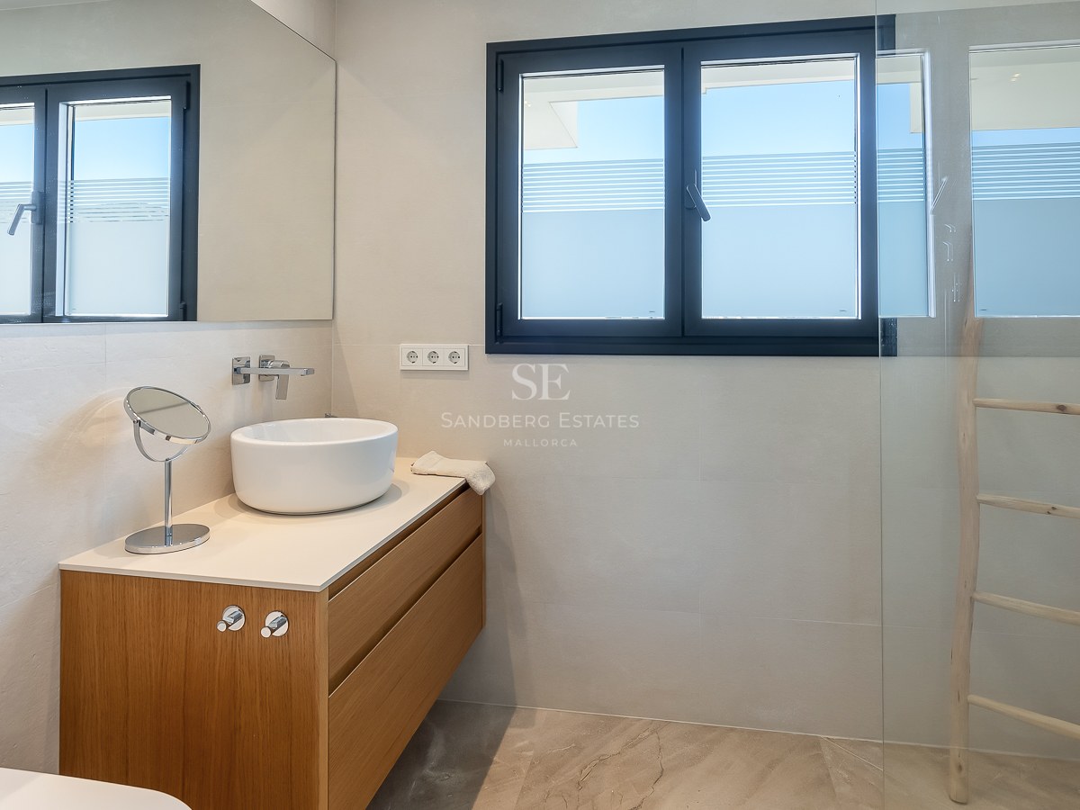 Salle de bain contemporaine avec vasque blanche sur meuble en chêne et douche vitrée.