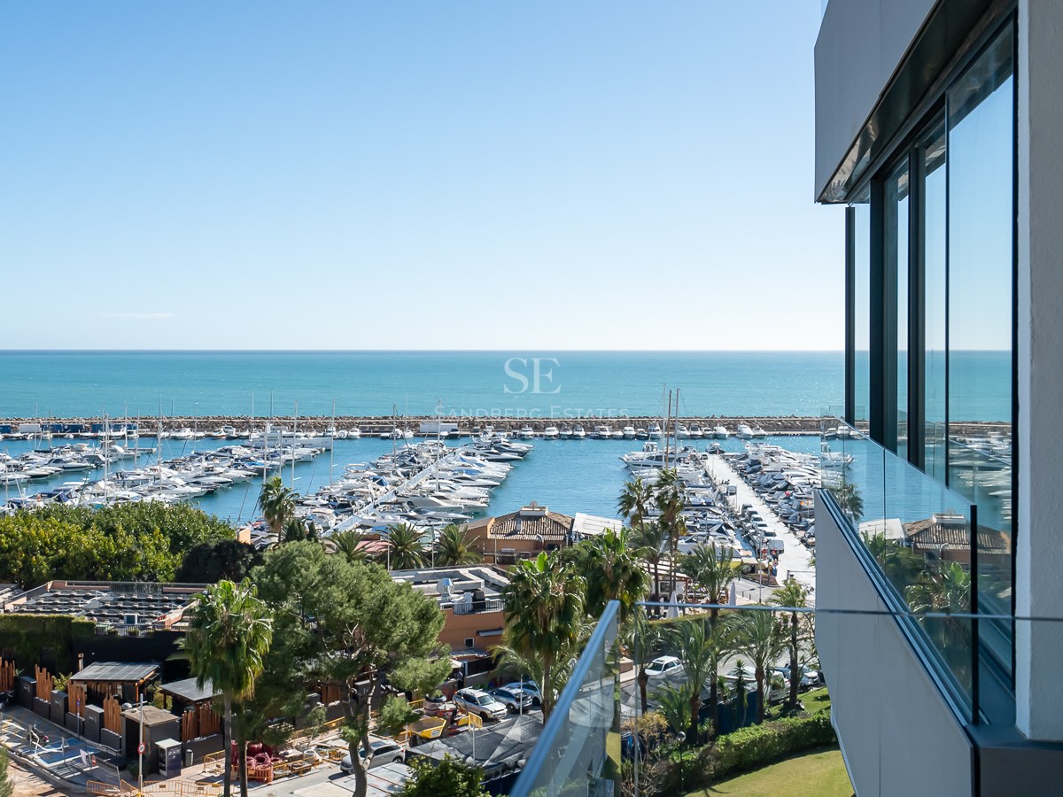 Vue surélevée depuis un balcon moderne donnant sur un port de plaisance et la mer Méditerranée.