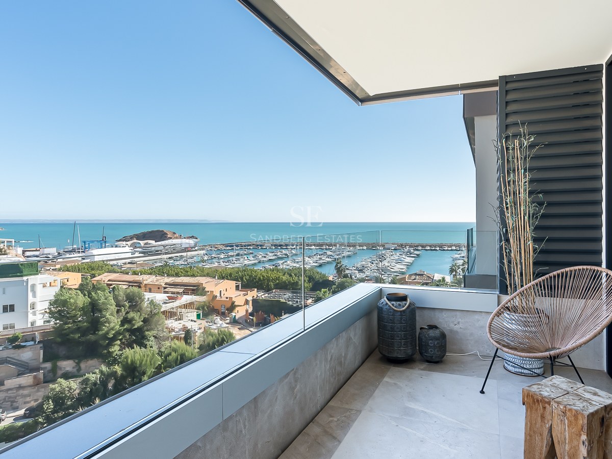 Balcon contemporain avec garde-corps en verre surplombant un port de plaisance et la mer Méditerranée.